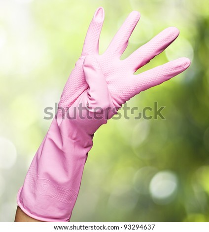pink glove of gesturing a number four against a nature background