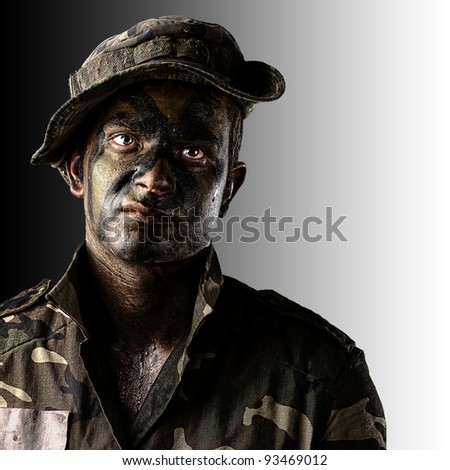 portrait of young soldier face with jungle camouflage over black and white background
