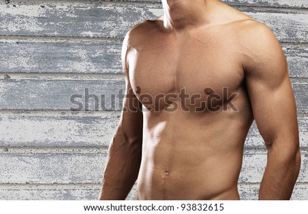 strong torso of young man against a grunge wall