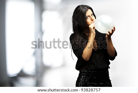 portrait of a young woman blowing up a balloon indoor