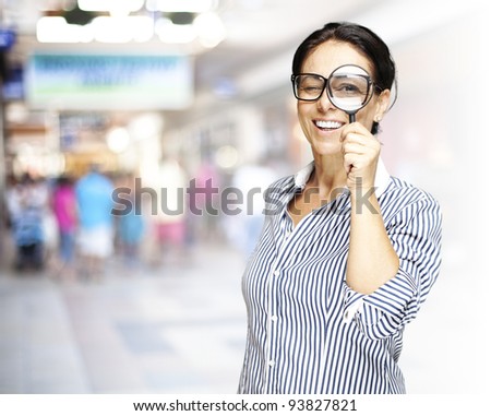 portrait of a middle aged woman looking through a magnifying glass against a crowded place