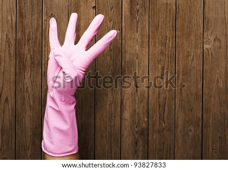 pink gloves of maid gesturing number four against a wooden wall