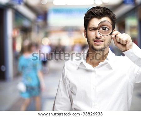 portrait of a young man holding a magnifying glass against a street background