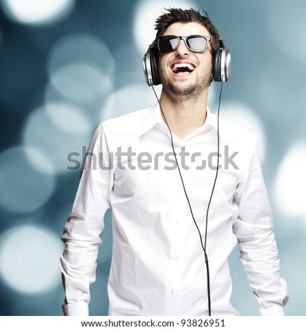 portrait of a young man listening to music with headphones against an abstract background