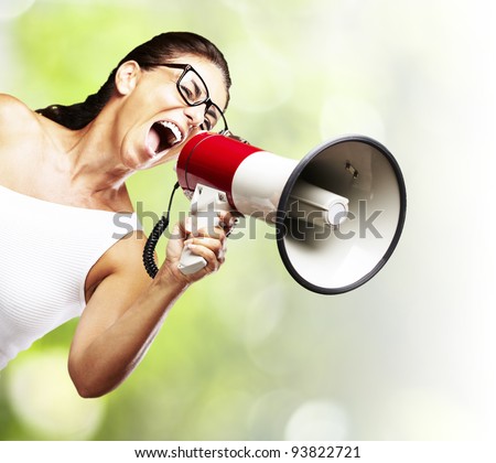 portrait of a middle aged woman shouting with a megaphone against a nature background
