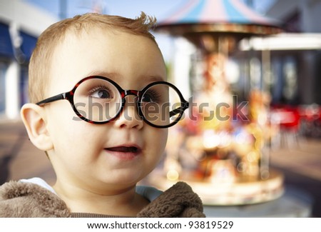 stock photo portrait of a kid wearing round glasses against a carousel