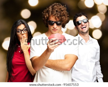 young man playing poker with friends against a abstract lights background