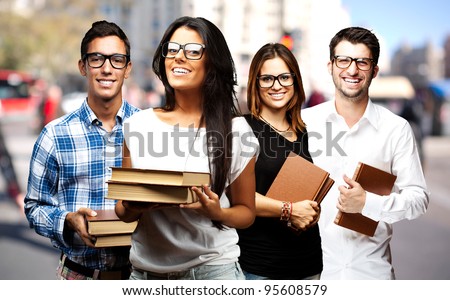 portrait of young students holding books at street