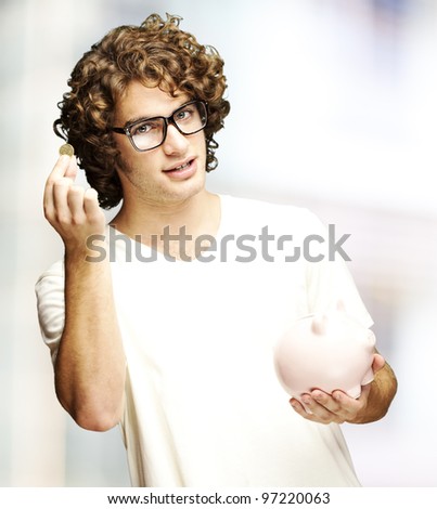 portrait of a young man holding a coin and a piggy bank indoor