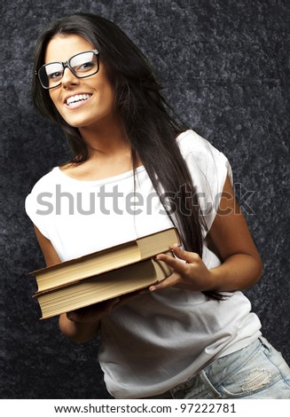 portrait of a young girl holding books against a grunge wall