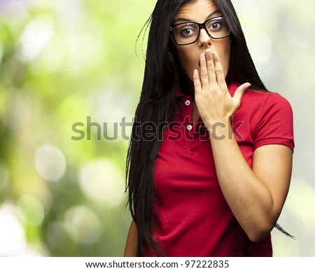 portrait of a young woman covering her mouth with her hand against a nature background