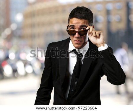 portrait of a business man taking off the sunglasses at a crowded city
