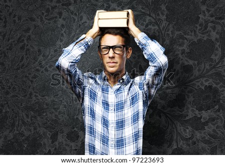young student holding books on the head against a vintage wall