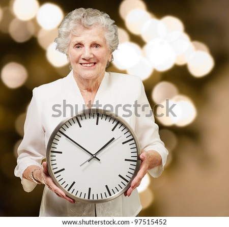 portrait of a happy senior woman holding clock against a abstract background