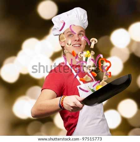 portrait of young cook man cooking vegetables against a abstract background