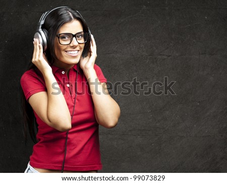 portrait of young woman listening to music against a grunge wall