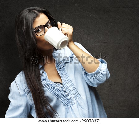 portrait of young woman drinking coffee against a grunge wall