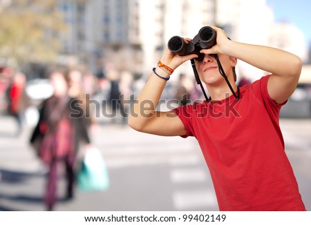 portrait of young man with binoculars at crowded street