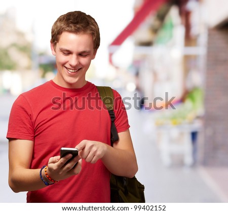 portrait of young man touching mobile screen at street