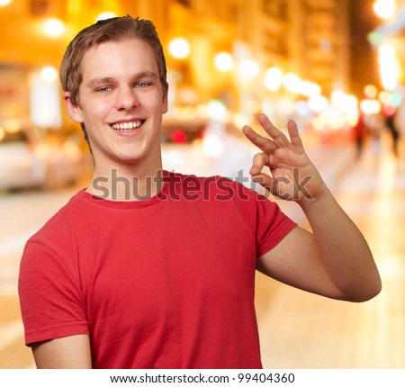 portrait of young man doing good gesture at night city