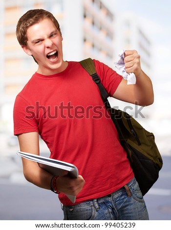 young angry student man roughing a sheet against a university