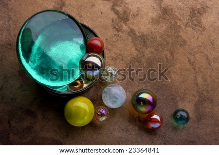 A toy marble collection spilling out of a silver and glass container