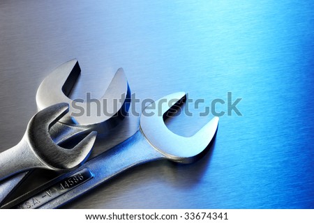 Three steel wrenches arranged on blue stainless steel background