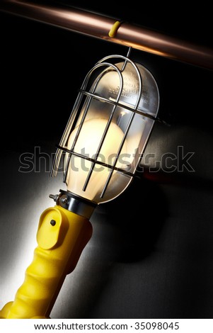 Mechanic\'s work lamp hanging from copper pipe