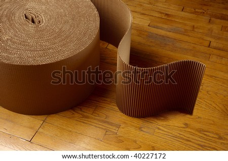 Roll of corrugated packing material uncurling on wooden floor
