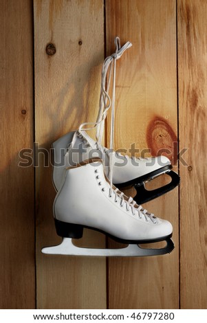Pair of woman\'s figure skates hanging inside barn with morning sun streaming in