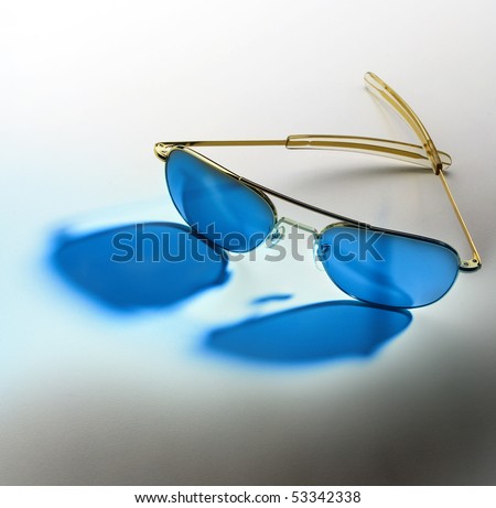 Sun glasses with blue lenses casting blue glow on background, space for copy