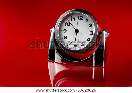 Silver desk clock shot on red background with reflection with space for copy