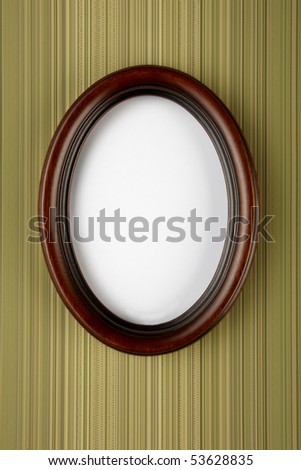 wooden oval picture frame shot on stripped wall paper with space for copy and photograph