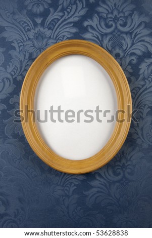 light wood, oval picture frame shot on blue, floral, flocked wall paper with space for photograph to be inserted and room for copy