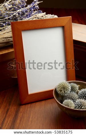 Blank desk frame shot on wood table with dried flowers, basket and box, space to add photograph and copy