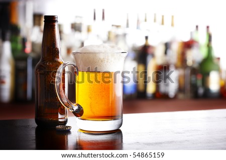 A full mug of beer with bottle and cap shot in bar
