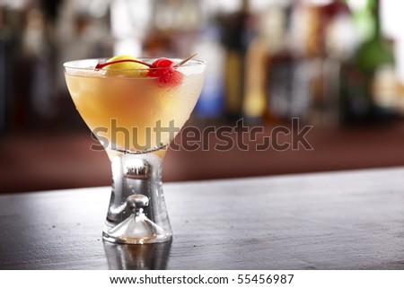 Chilled glass filled with whiskey sour, cherry and lemon shot in bar