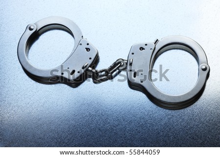 Pair of locked handcuffs shot on steely cool metallic background