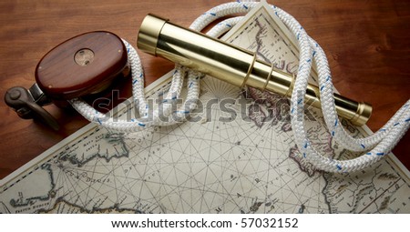 Wooden pulley, white nautical rope, antique, brass telescope and navigational map shot on boat deck