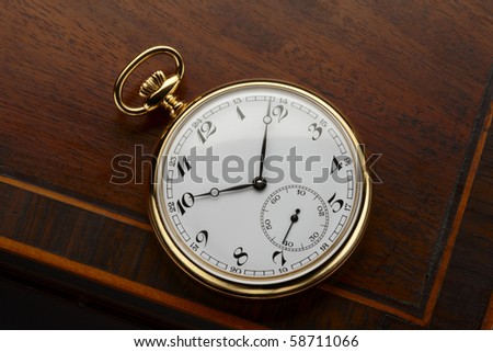 close up of antique pocket watch shot on antique wooden surface, space for copy