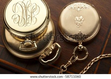 Close up of three vintage, gold pocket watches shot on antique wooden box