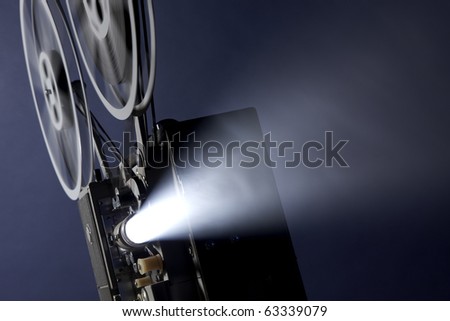 Angled 16mm movie projector projecting images through smoky background with space for copy