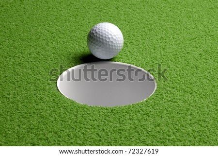 Close up shot of golf ball about to drop into hole, includes space for copy