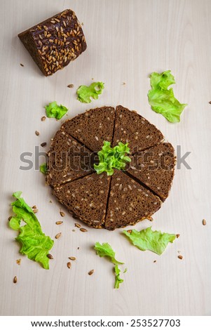 The composition of the bread with sunflower seeds in the form of a circle with a green salad leaves