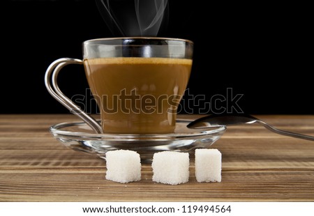 cup of coffee and pieces of sugar on wooden table
