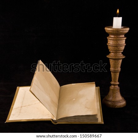 old books with a candle on a black background