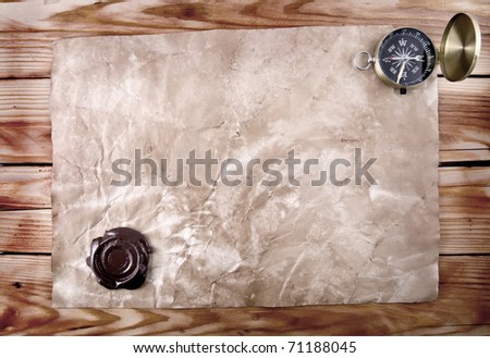 compass and old paper with printing to the wooden background