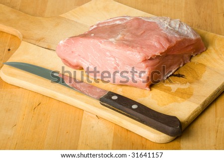 raw pork meat on board with knife