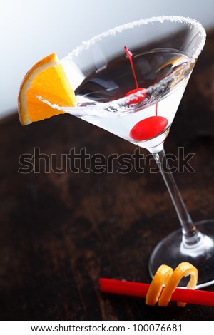 Dry Martini with a cherry and an slice of orange fruit on an aged background