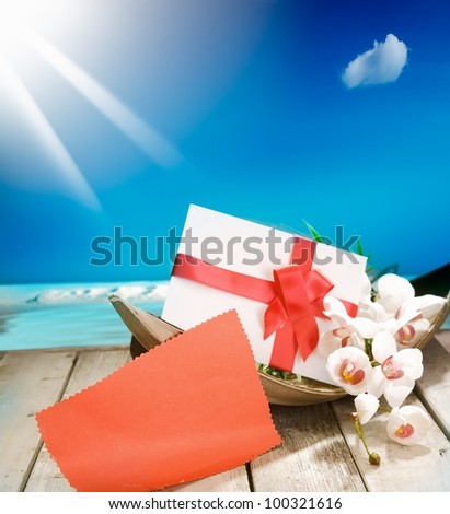 Voucher in a palm bowl with a bow at a deck in front of the deep blue pacific ocean and a shiny sun. With copyspace for your own Text and messages